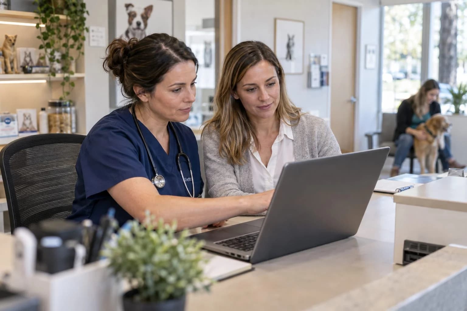 Two clinic team members review software on a laptop at reception.